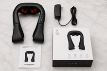 Black neck and shoulder massager shown with its power adapter, instruction manual, and retail box on a light marble surface.
